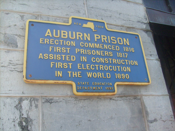 A 1932 State Education Department plaque on the entrance to Auburn Prison which reads: "ERECTION COMMENCED 1916, FIRST PRISONERS 1817 ASSISTED IN CONSTRUCTION, FIRST ELECTROCUTION IN THE WORLD 1890"