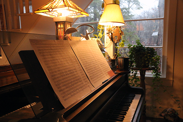 Hagen's grand piano with a manuscript score illuminated by overhead lamps.