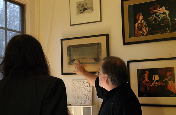 Daron Hagen points at a detail of a photo in a frame on the wall as FJO looks on.
