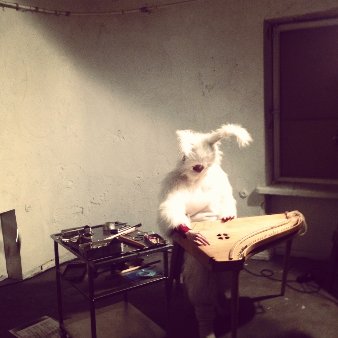 A musician in a bunny suit performing on the traditional Estonian kannel