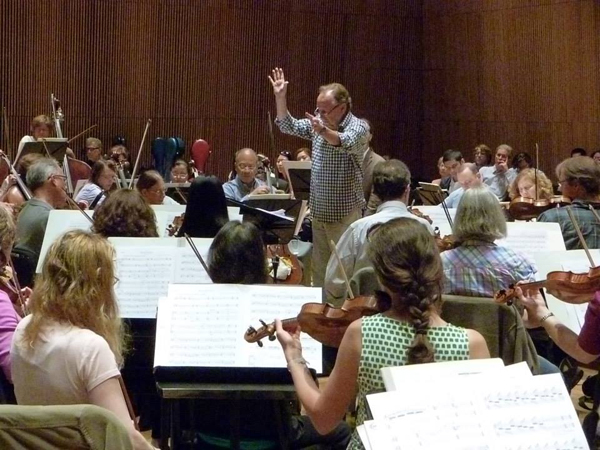 Musicians in an orchestra rehearsing with a conductor