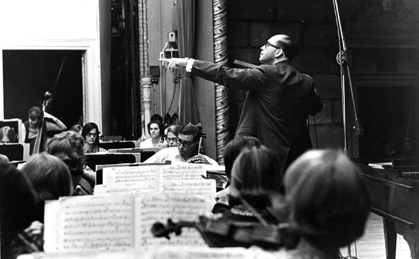 Side view of Adler with arm raised conducting an orchestra