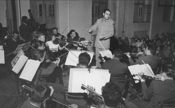 Adler in military uniform conducting an orchestra in front of an audience