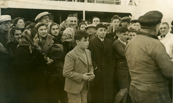 An historic black and white photo of a crowd of people gathered together on the deck of a boat.