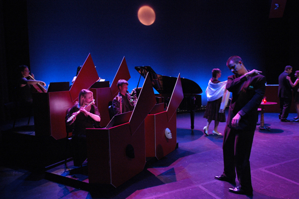 Members of the Pittsburgh New Music Ensemble in a staged performance with dancers and a projected image of the moon