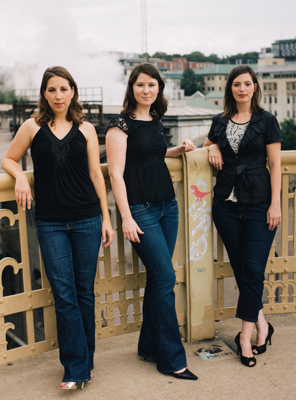 The three members of the Trillium Ensemble: standing and leaning on a fence.
