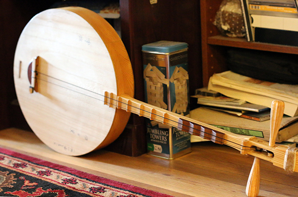 A two-stringed moon lute resting horizontally on the floor next to a rug and a puzzle.