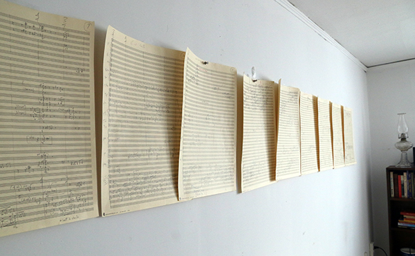 Pages of a manuscript of an orchestral score on a wall.