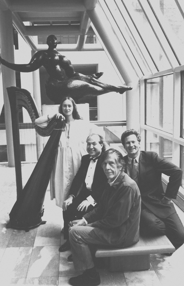 Alyssa Hess standing and leaning on a harp with Charlie Morrow, John Cage and R.I.P. Hayman seated in front of her. 