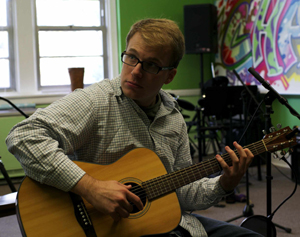 Chris Cresswell fingering a chord on a guitar and strumming it.