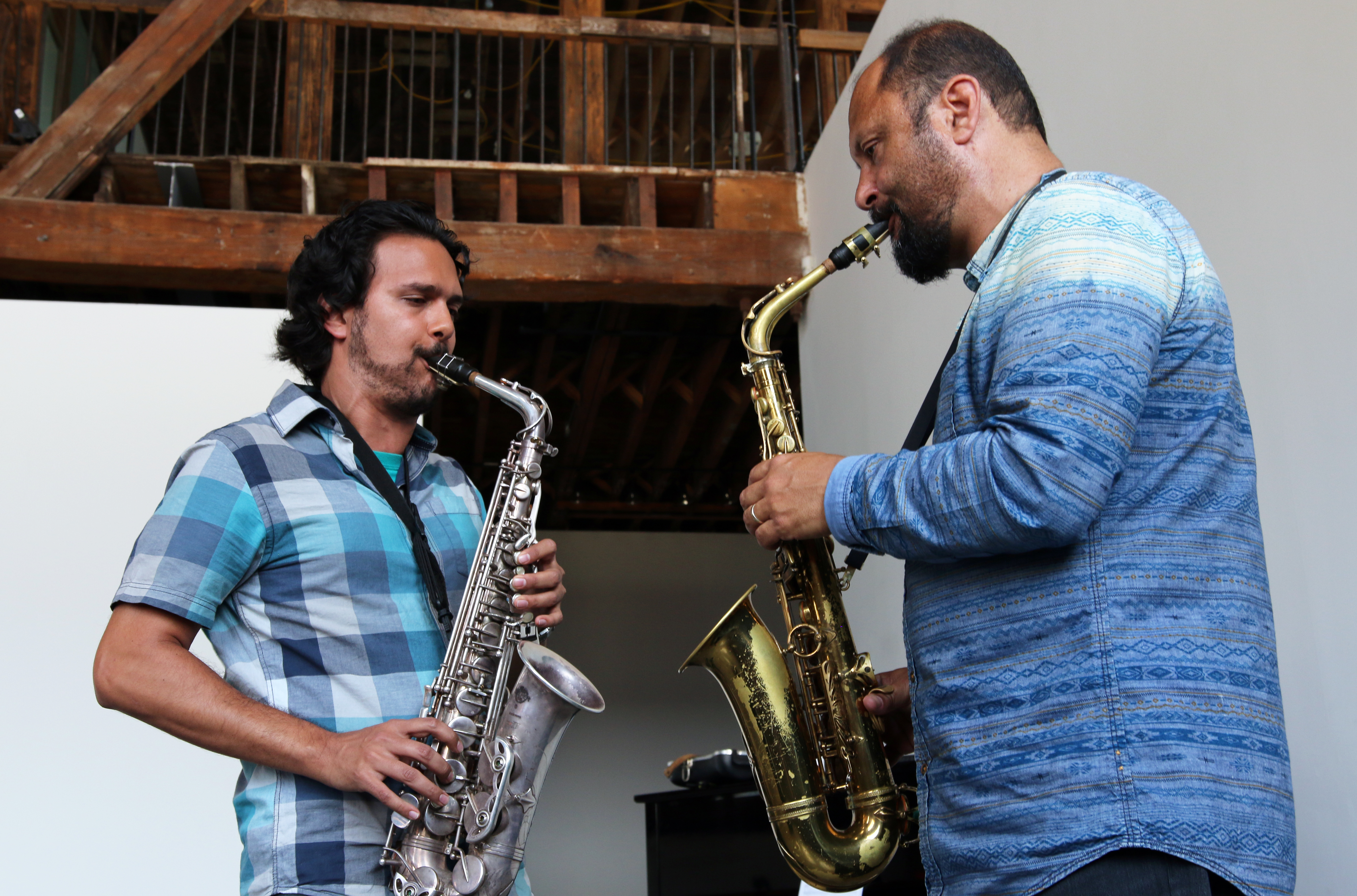 Aakash Mittal and Hafez Modirzadeh facing each other playing alto saxophones.