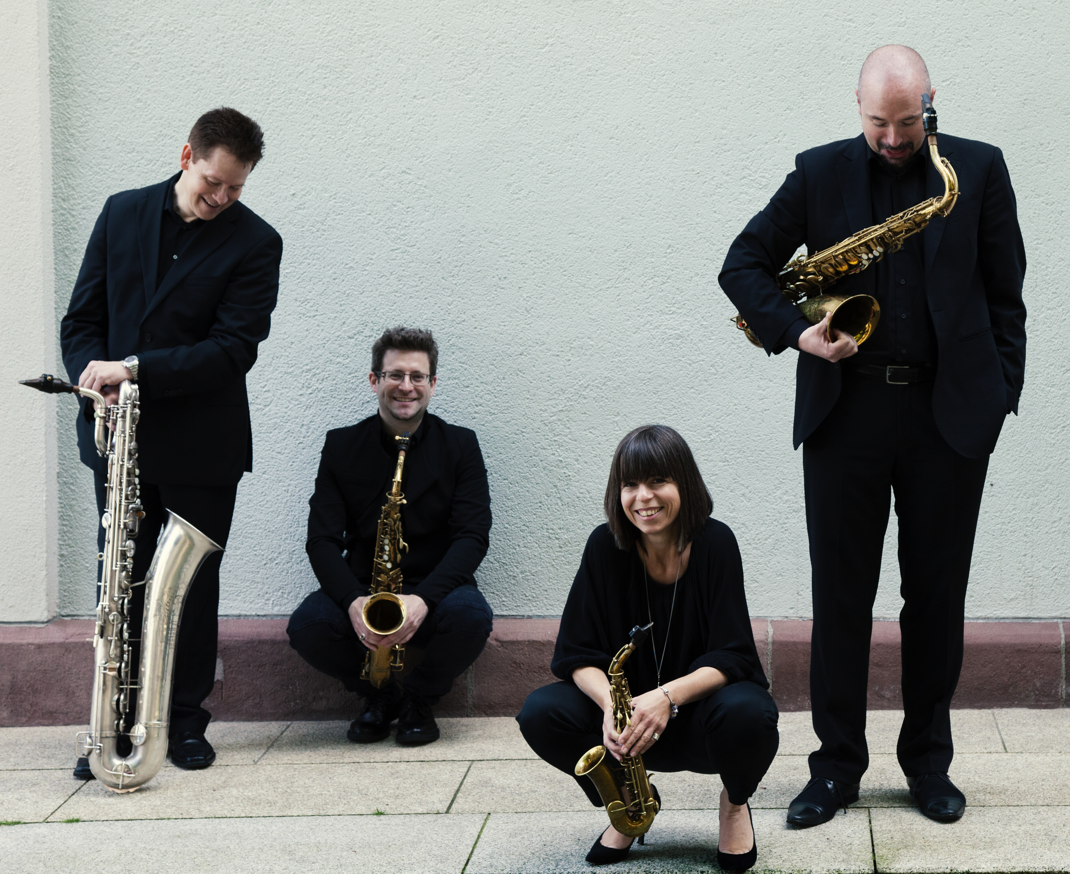 The Rascher Quartet holding their instruments which include a curved soprano saxophone.