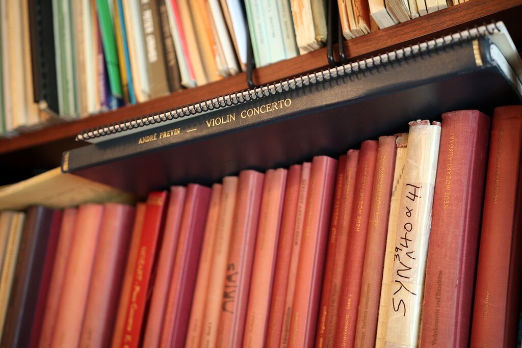 A bound score of Previn's Violin Concerto sits on top of a row of bound scores that fill up Previn's shelves.