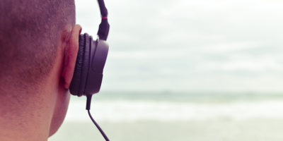 closeup of a young man listening to music with headphones in front of the sea, with a filter effect