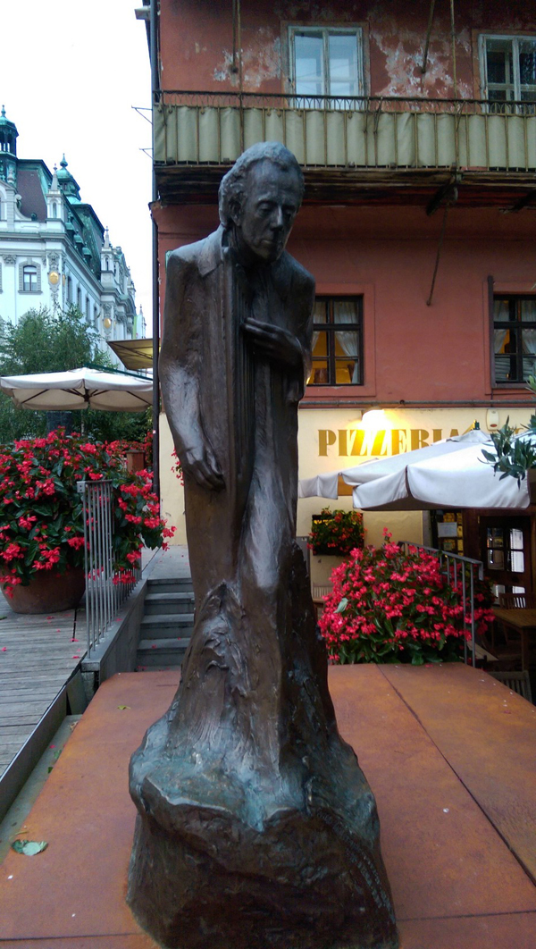A statue of the composer Gustav Maher in front of a pizzeria.