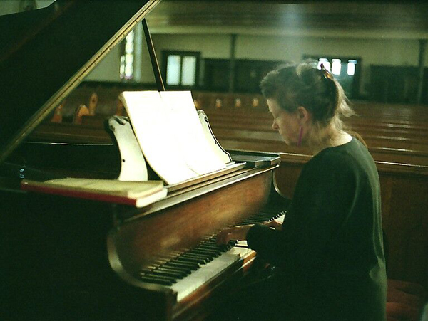 Mary Jane Leach playing a grand piano in a church.