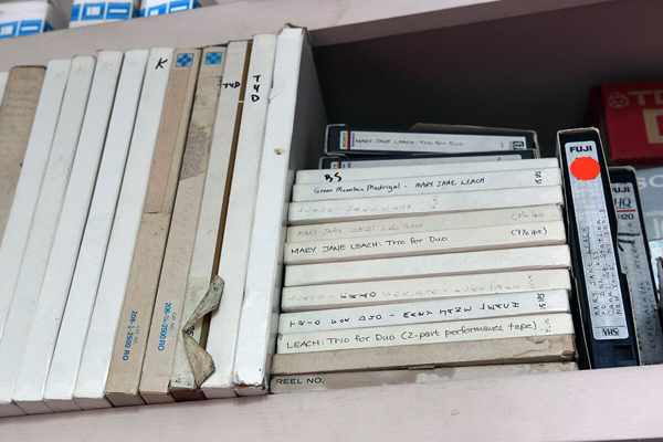 A shelf full of boxes containing reel-to-reel tapes.