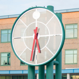 A large clock displaying the time 5:32 in front of a building.