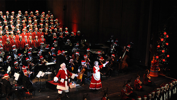 Orchestra performing with some players dressed in Santa Claus costumes.