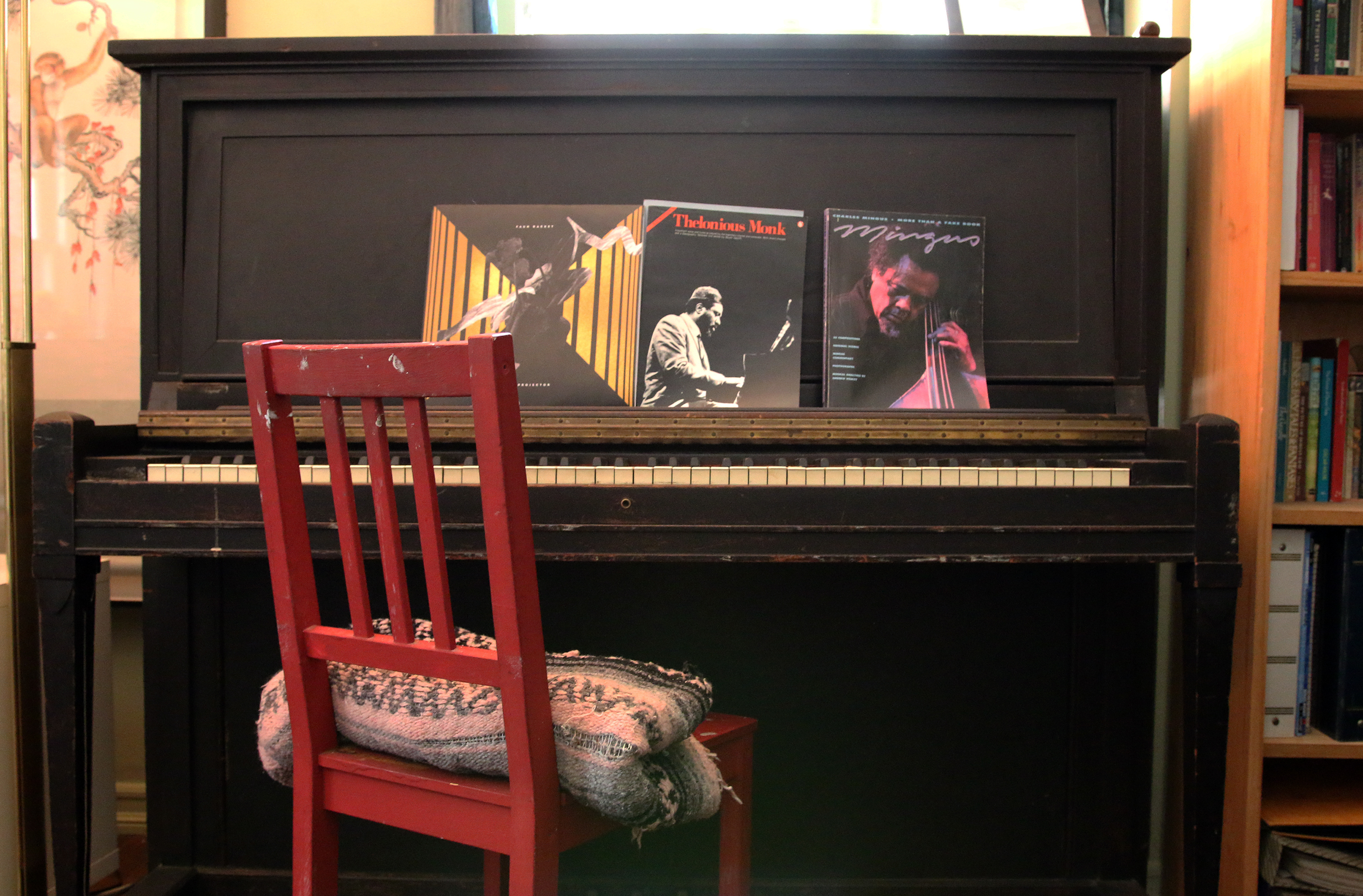 The upright piano in John King's apartment which has books of scores by Thelonious Monk and Charles Mingus.