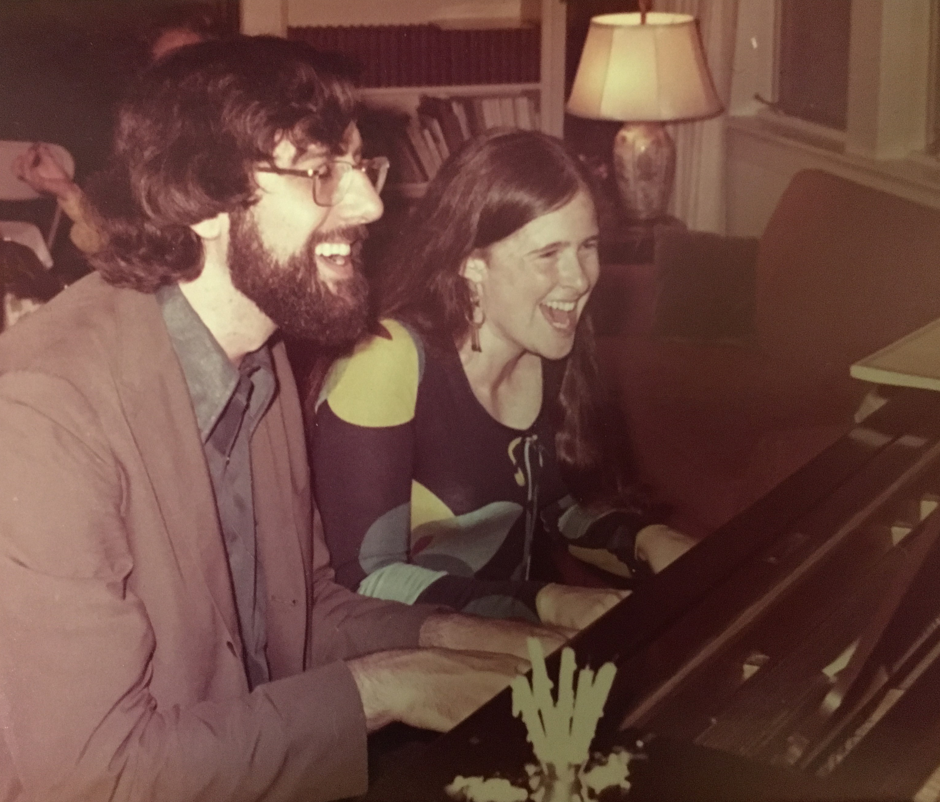Joel Gressel and Eleanor Cory laughing while playing on a piano together.