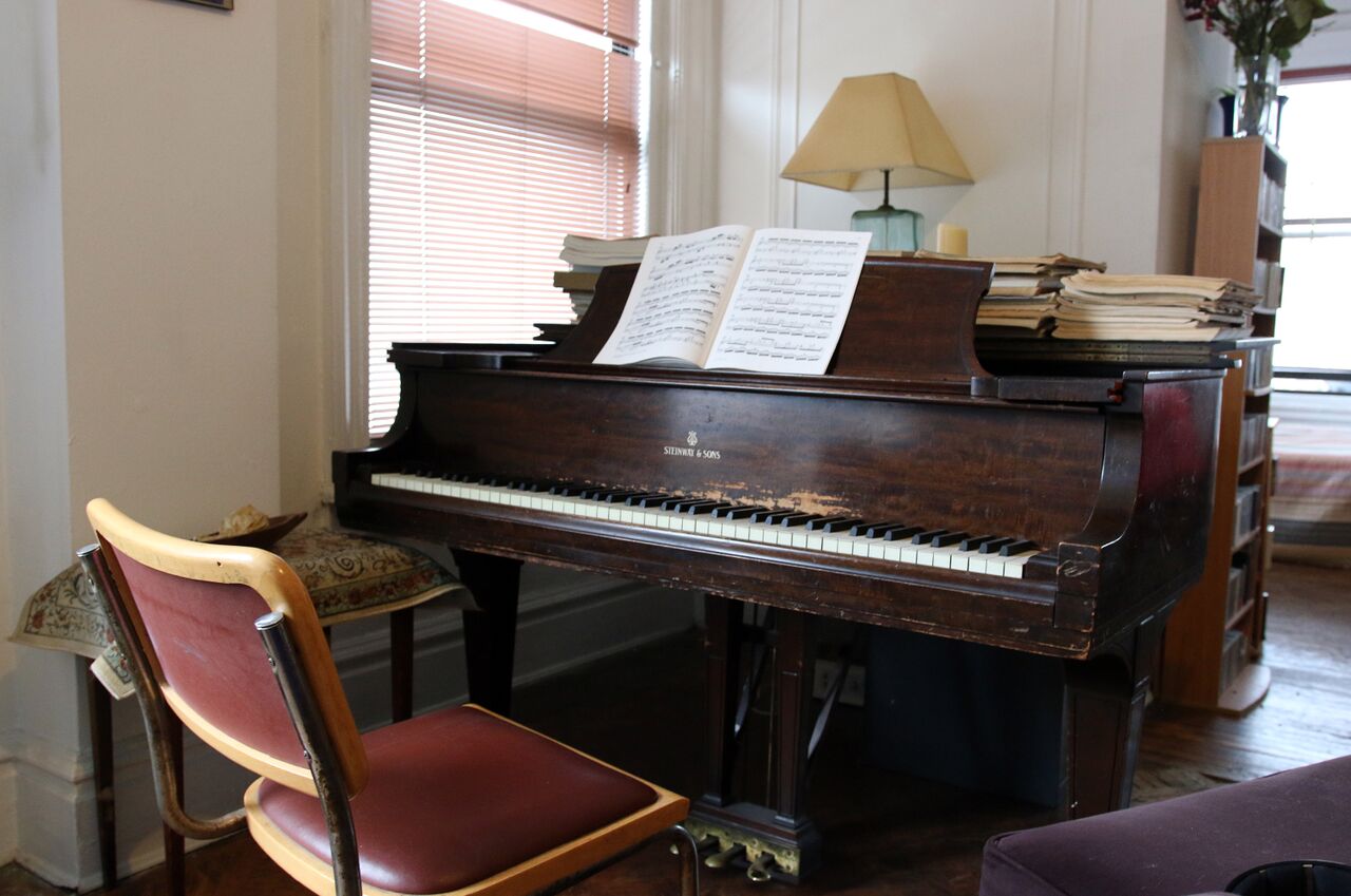 A Steinway grand piano with an open score on its music rack.