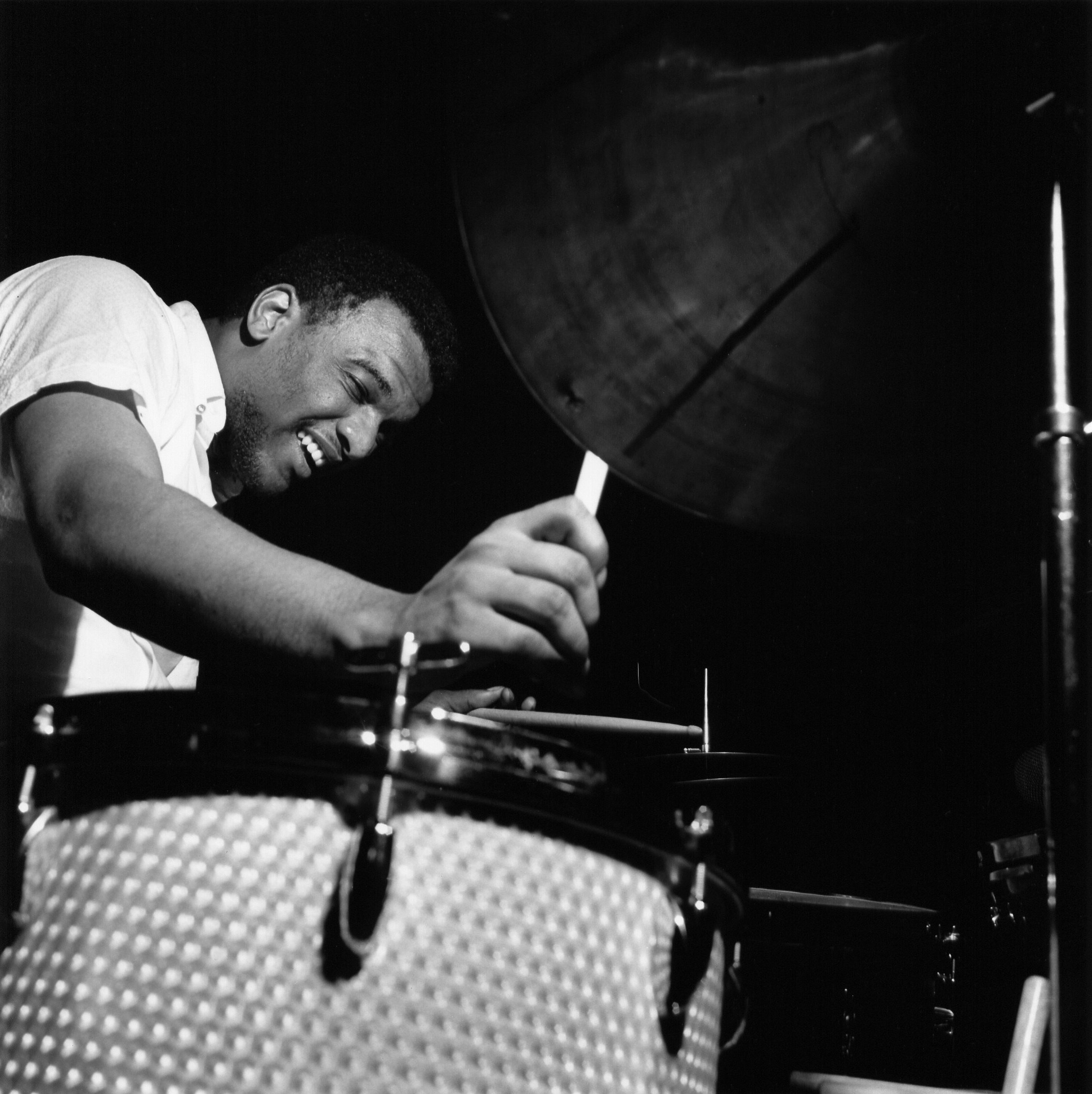1965 black and white Blue Note Records photo by Francis Wolff of Joe Chambers playing drums during a recording session.