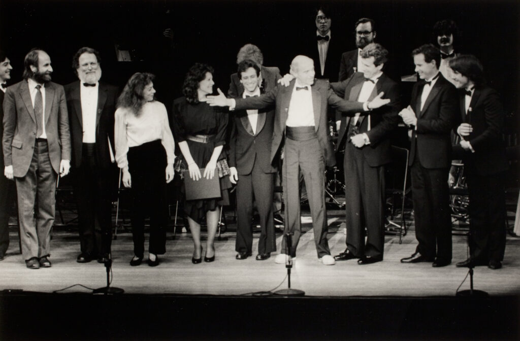 Peaslee (center) on the stage of Alice Tully Hall in 1989 with (starting on the left) cellist Eugene Friesen, composer Peter Schickele, choreographer Martha Clarke, singer Jim Naughton, and orchestrator Bruce Coughlin at the end of the Composers' Showcase tribute to Richard Peaslee.