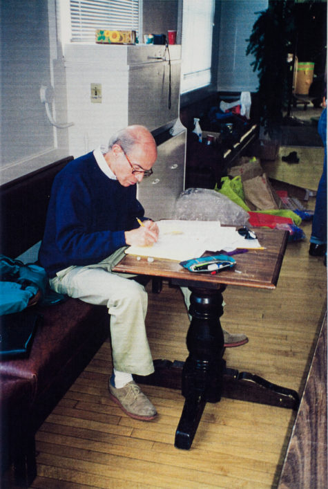 Peaslee writing music on manuscript paper on a table.