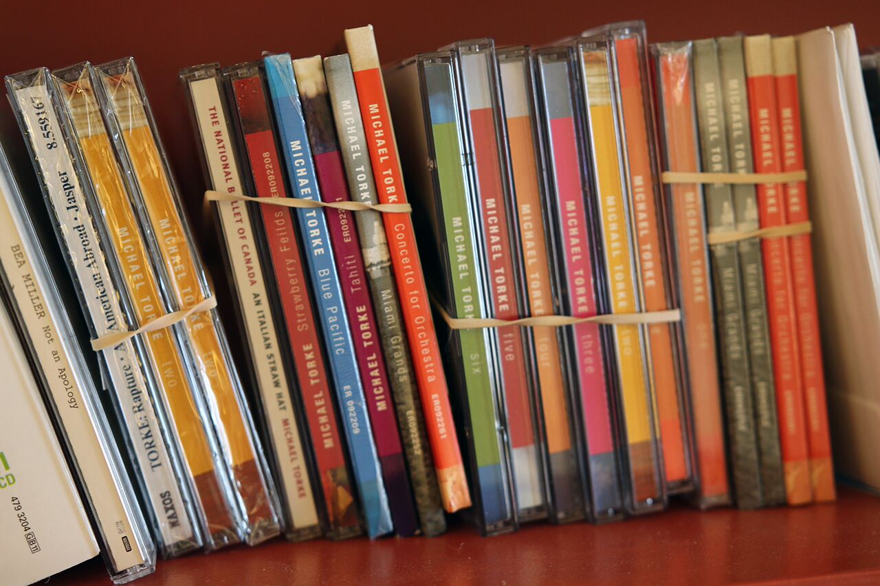 A shelf with bundles of Torke CDs grouped together with rubber bands.