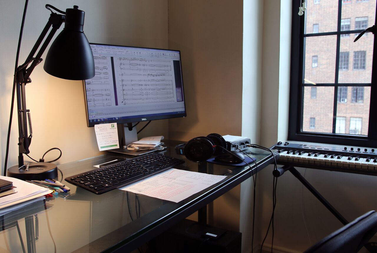 Michael Torke's spare work desk contains just a lamp, a computer with an oversized monitor; a digital piano is off to the side.