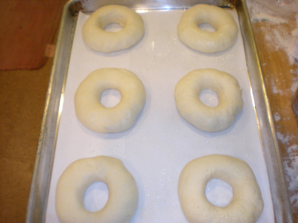 Six bagels on a tray in the process of being baked