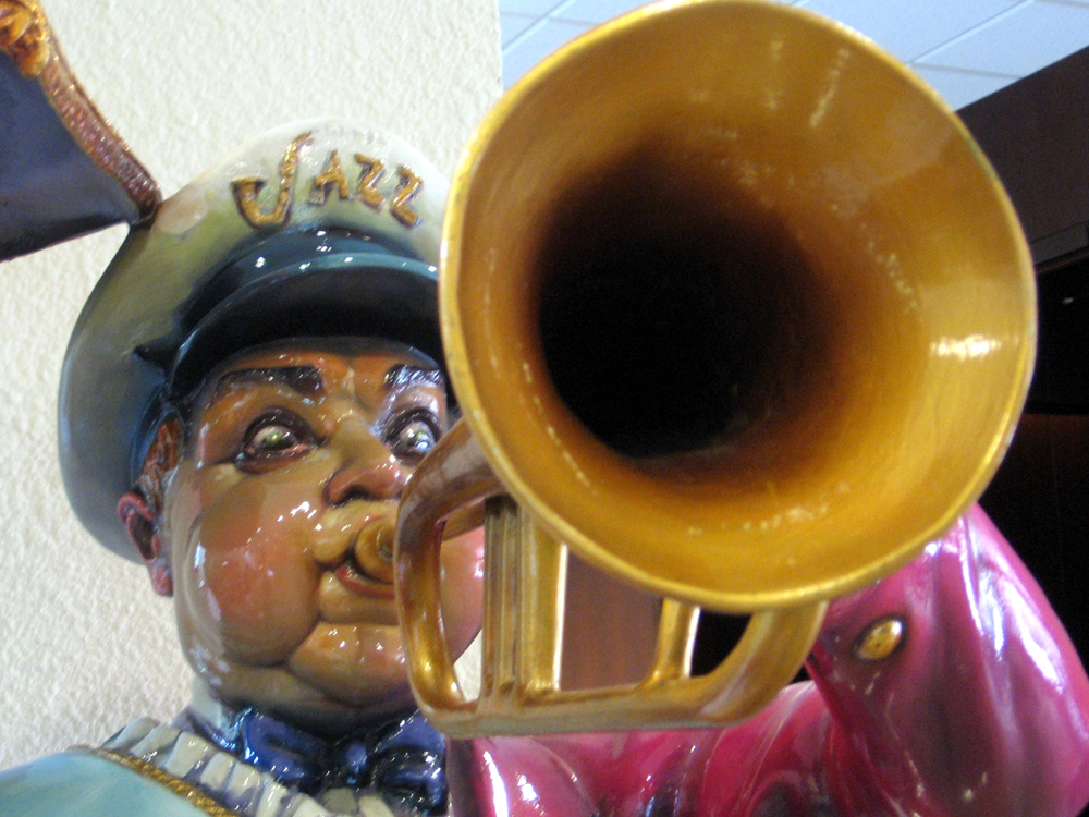 Porcelain statue resembling Louis Armstrong playing a trumpet and wearing a cap that says "jazz"; image by jbarreiros https://www.flickr.com/photos/tintedglasssky/ 