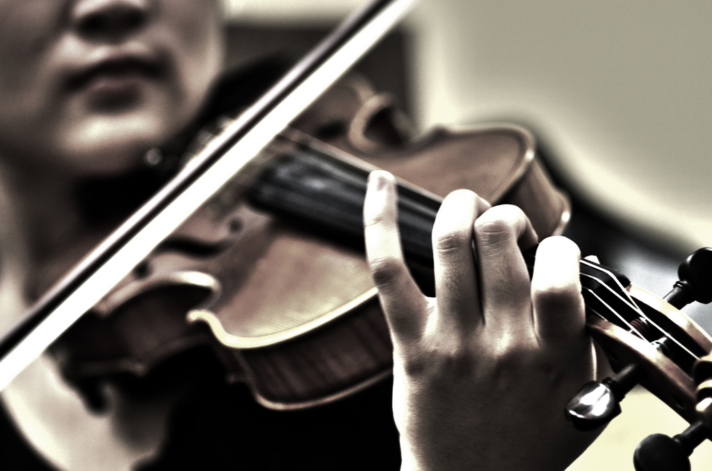 Violinist bowing on a violin in standard classical music playing position (under the chin)