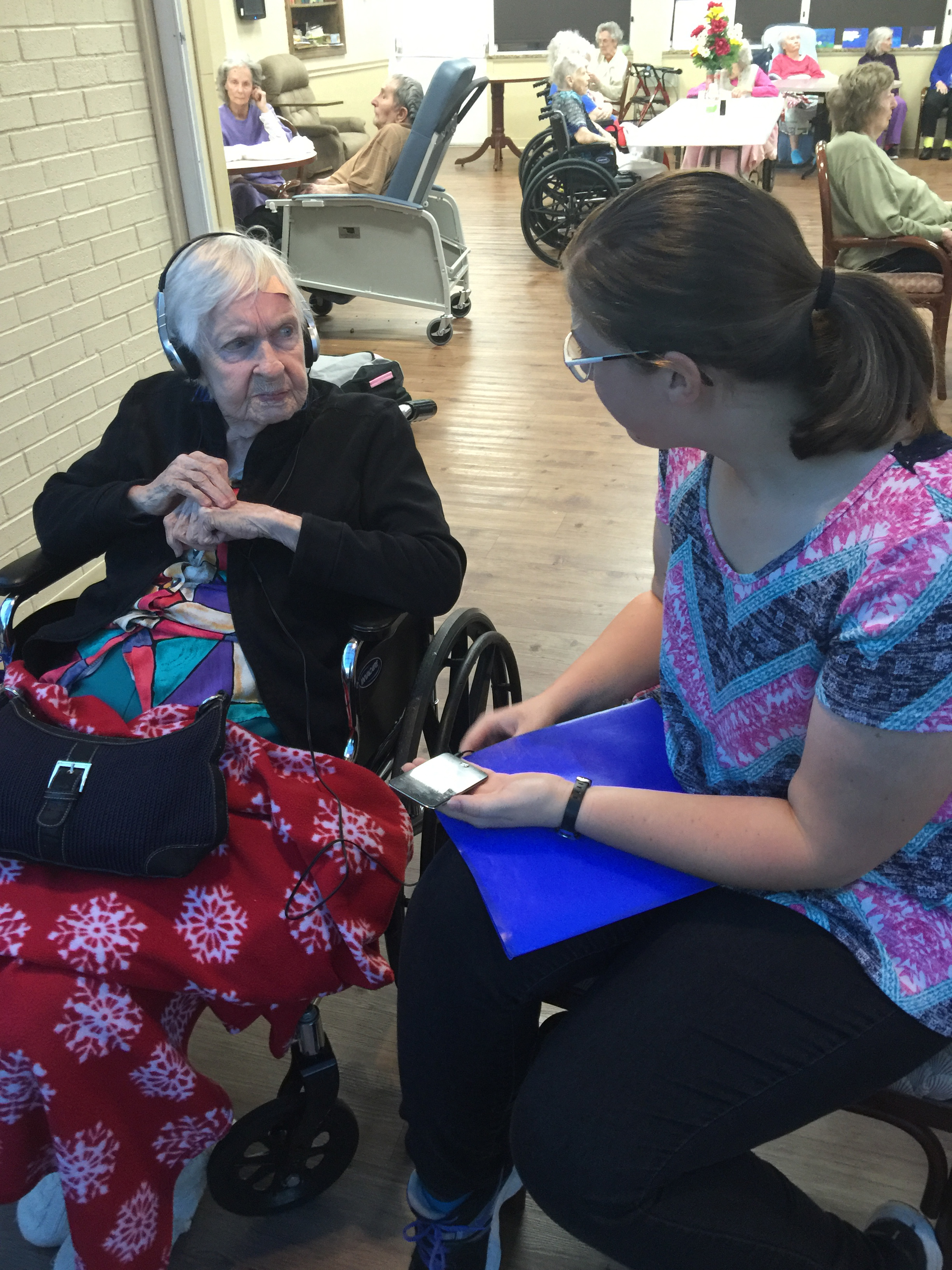 Music and Memory team member Jennifer Watson talking with one of the residents who is seated in a wheelchair.