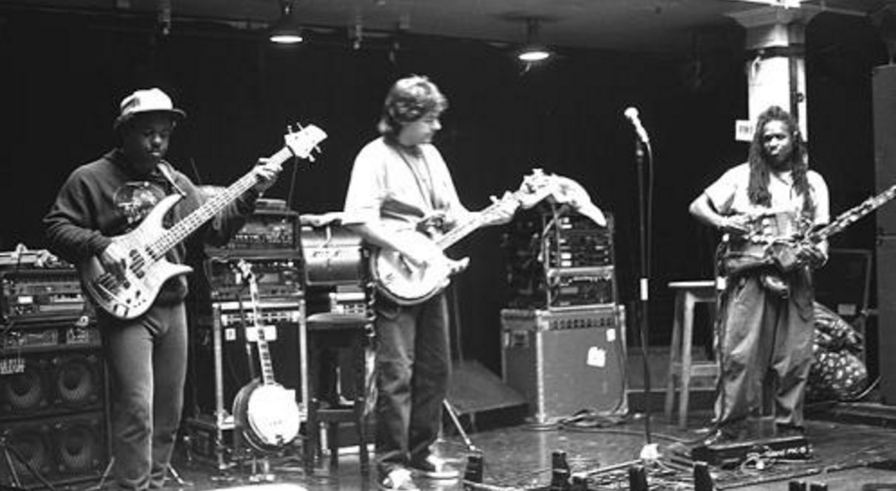 Béla Fleck (center) in performance with the Flecktones: Victor Wooten (far left, playing electric bass guitar), his Roy Wooten a.k.a. Future Man (far right, playing the Drumitar)