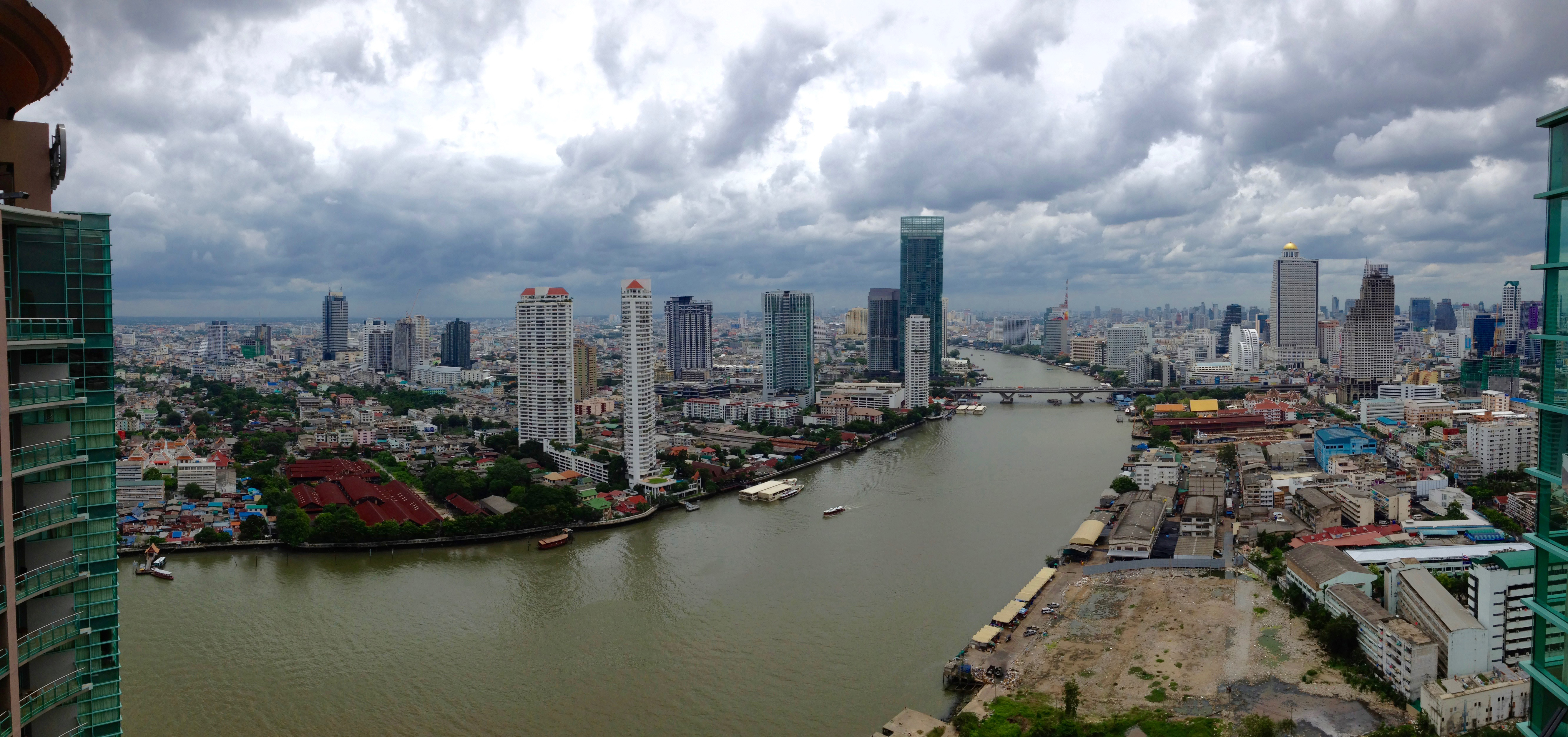 An aerial view of Bangkok showing skyscrapers on both sides of a river.