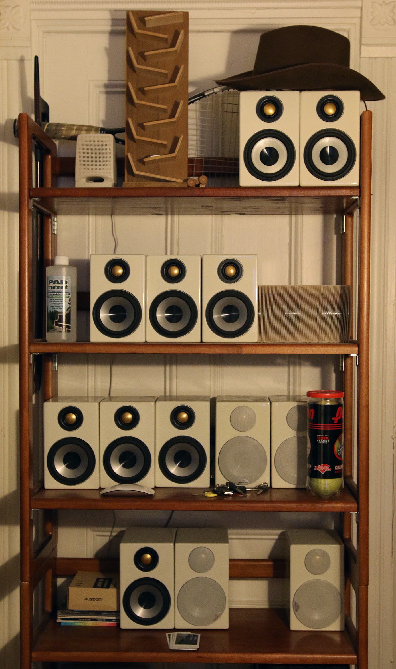 A bookcase in Schumacher's hallway that is filled with speakers and a hat on top of one of them.