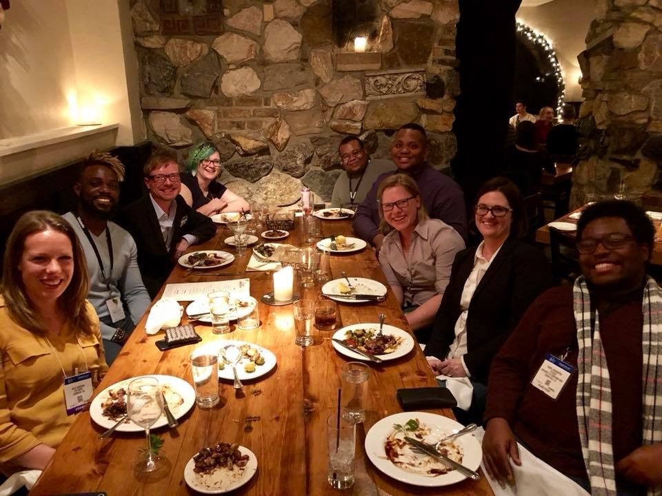The composers who were promoting their music at the Midwest Clinic's Osti Music booth sitting around a table with John Mackey having dinner.