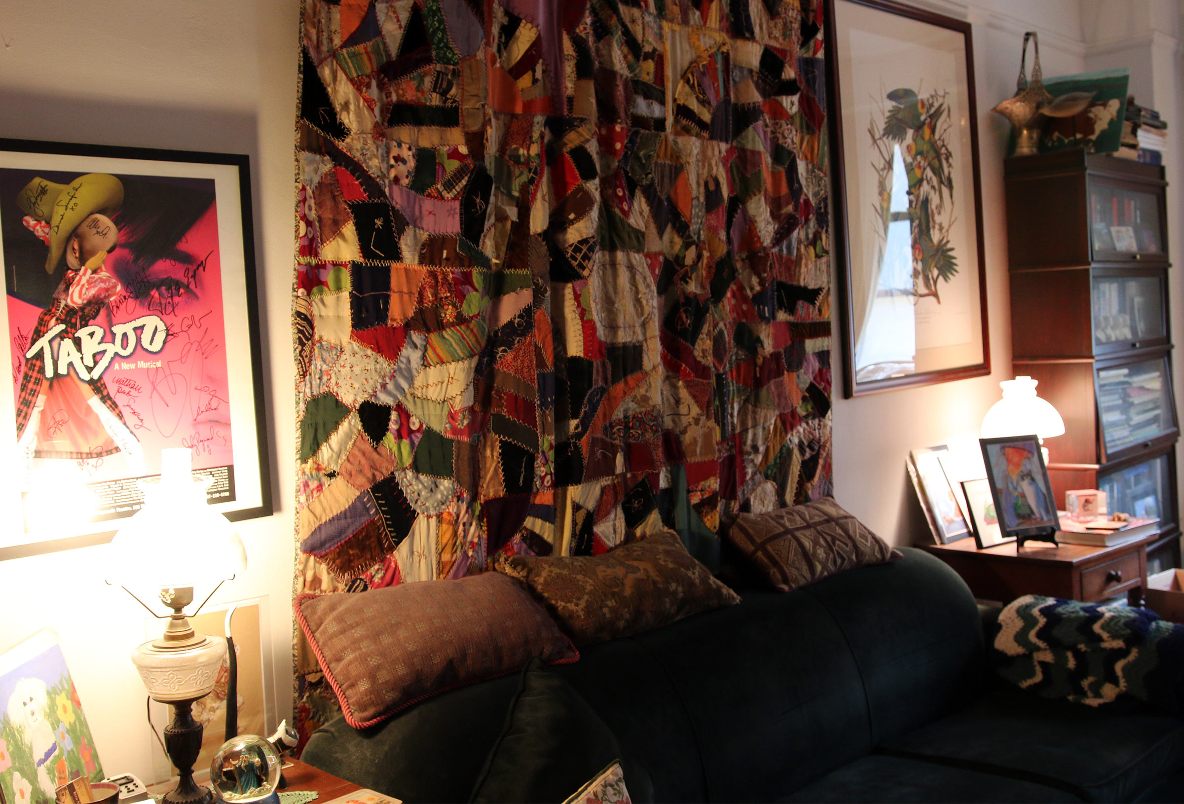 A view of the entire quilt hanging on one of the wall's oin Beth Anderson's living room behind a couch and in between two posters.