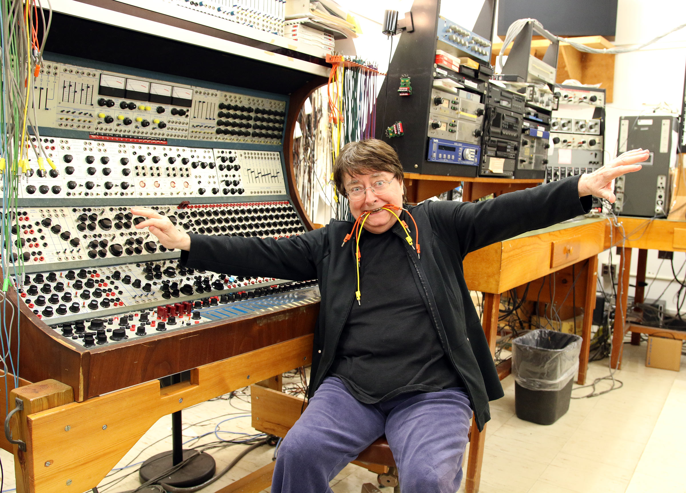 Daria Semegen with a bunch of wires in her mouth sitting in front of the Buchla synthesizer at the Stony Brook Electronic Music Center.