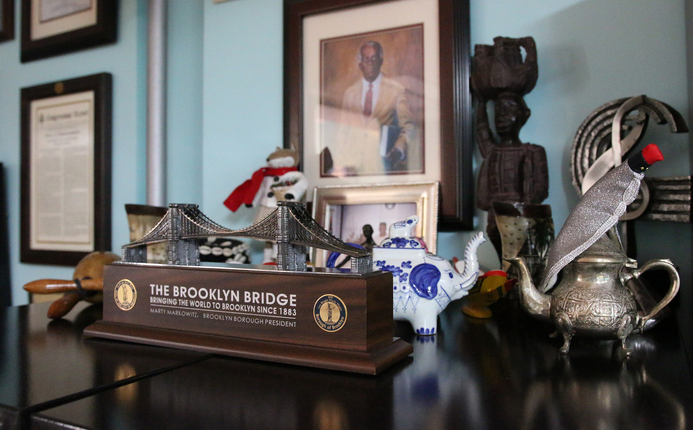 A shelf in Randy Weston's home featuring a variety of trinkets including a miniature model of the Brooklyn Bridge