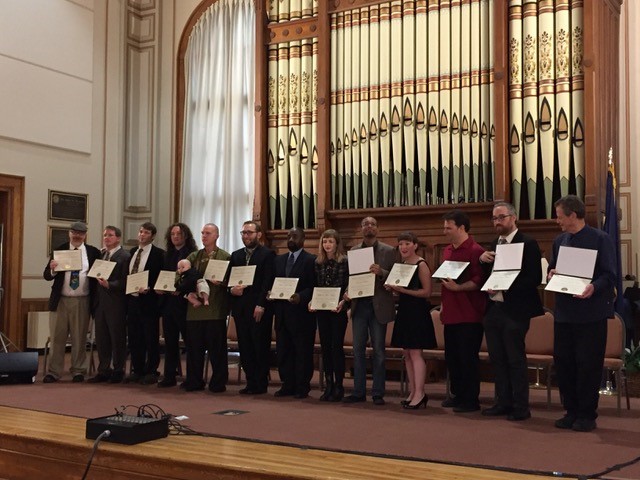 A photo of the 2016 VCFA graduating class in music composition during graduation all holding their diplomas.