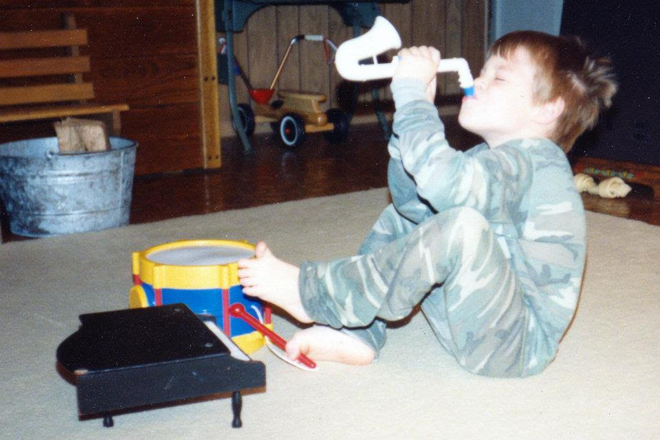 Garrett as a young child playing with a toy saxophone and a toy piano.