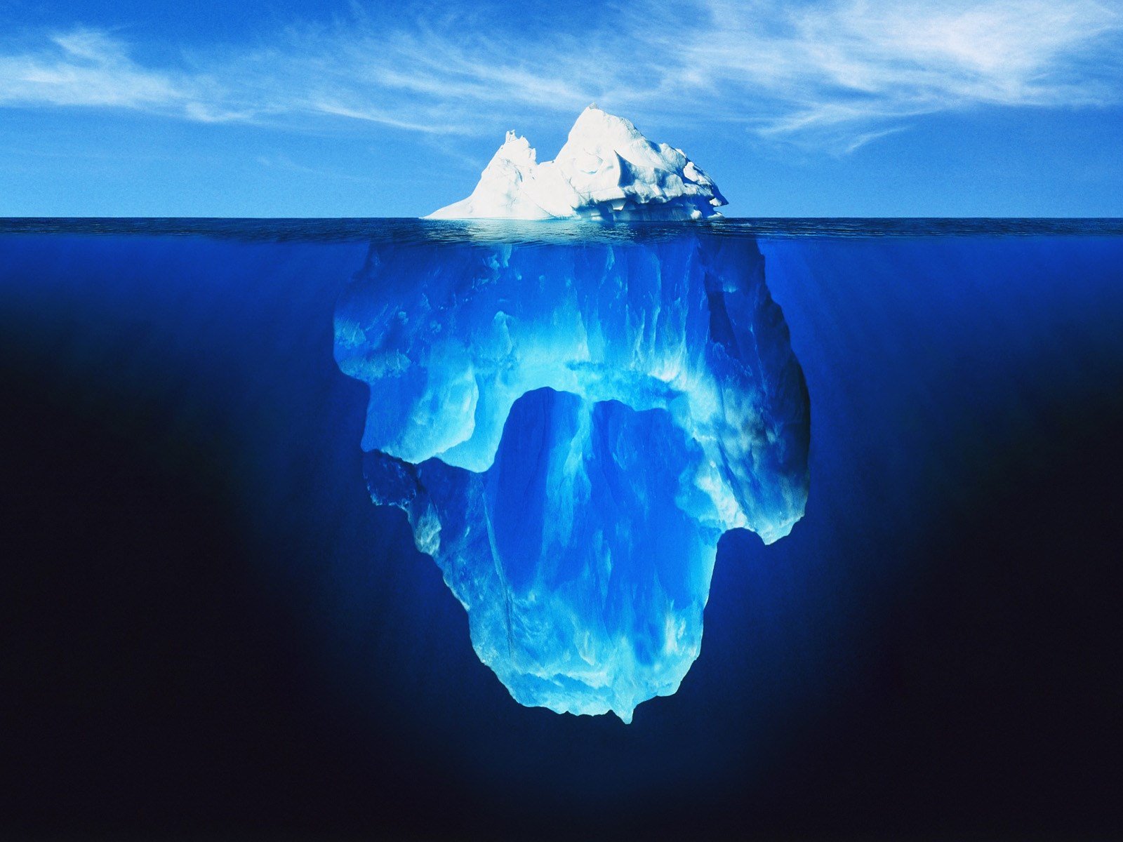 An iceberg partially above water but mostly below.