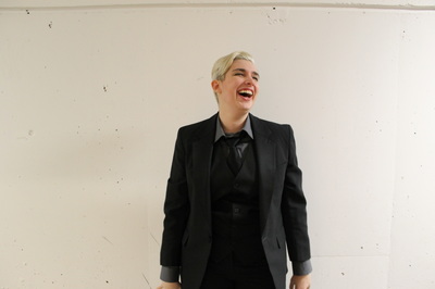 A nonbinary person wearing a suit laughing