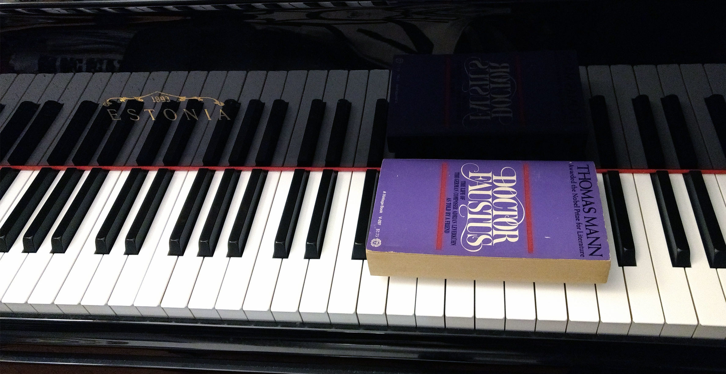 A paperback copy of an English translation of Thomas Mann's novel Doctor Faustus resting atop the keys of a piano.