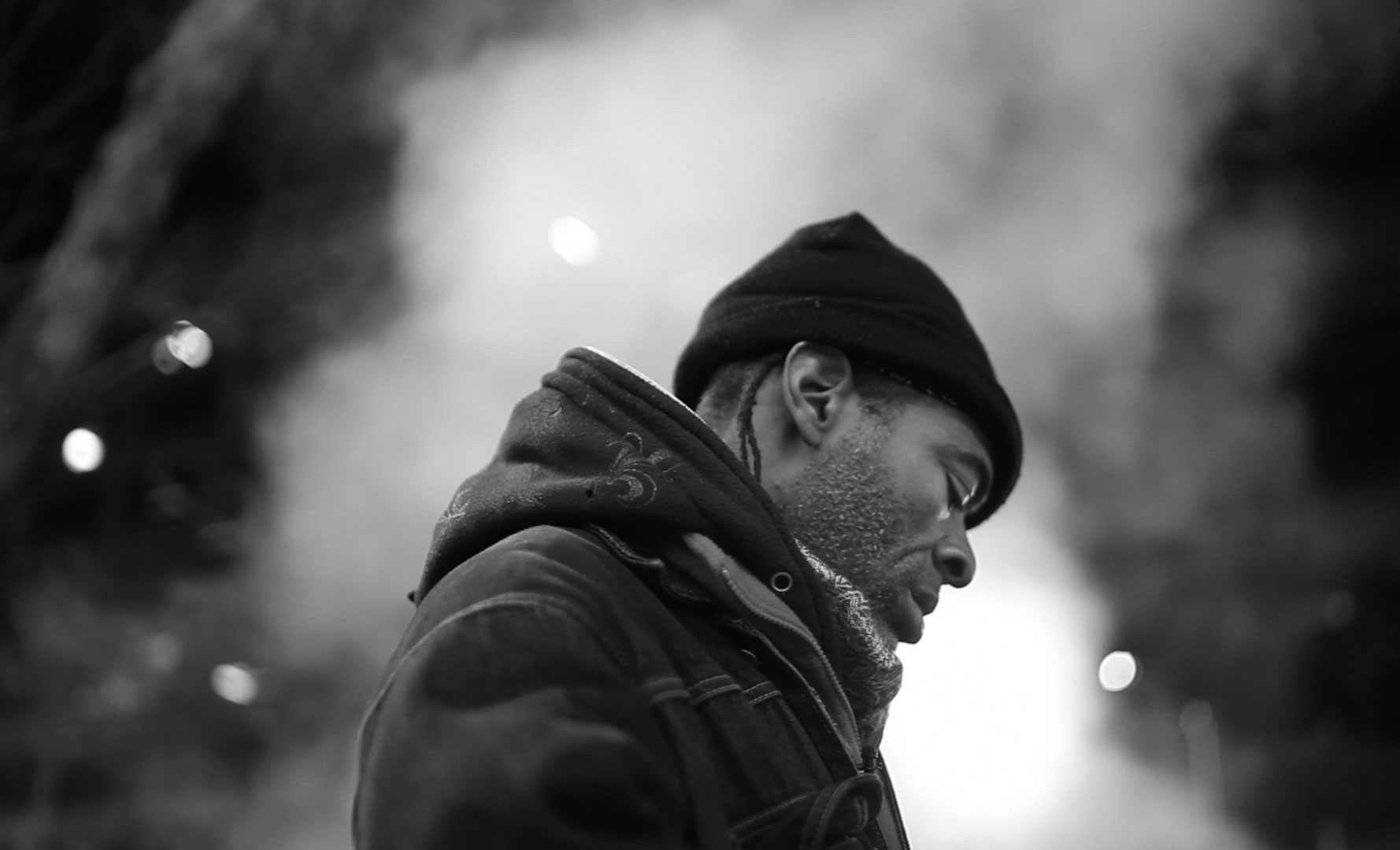 A smoky, black and white perspective shot of a man in a beanie