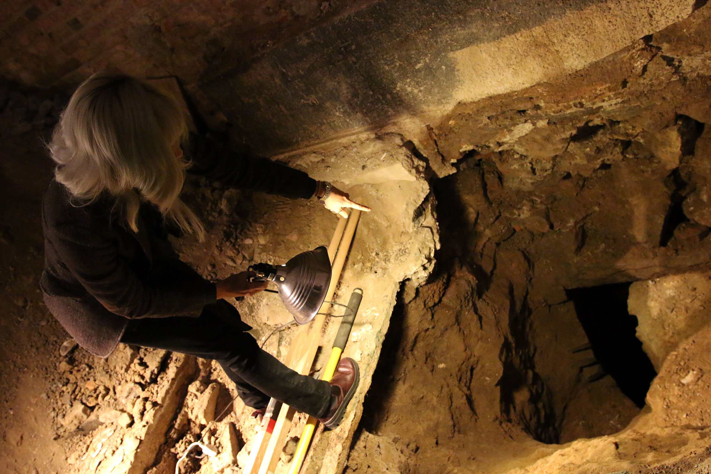 Melissa Dunphy standing next to a deep hole in the ground which once was a privy.