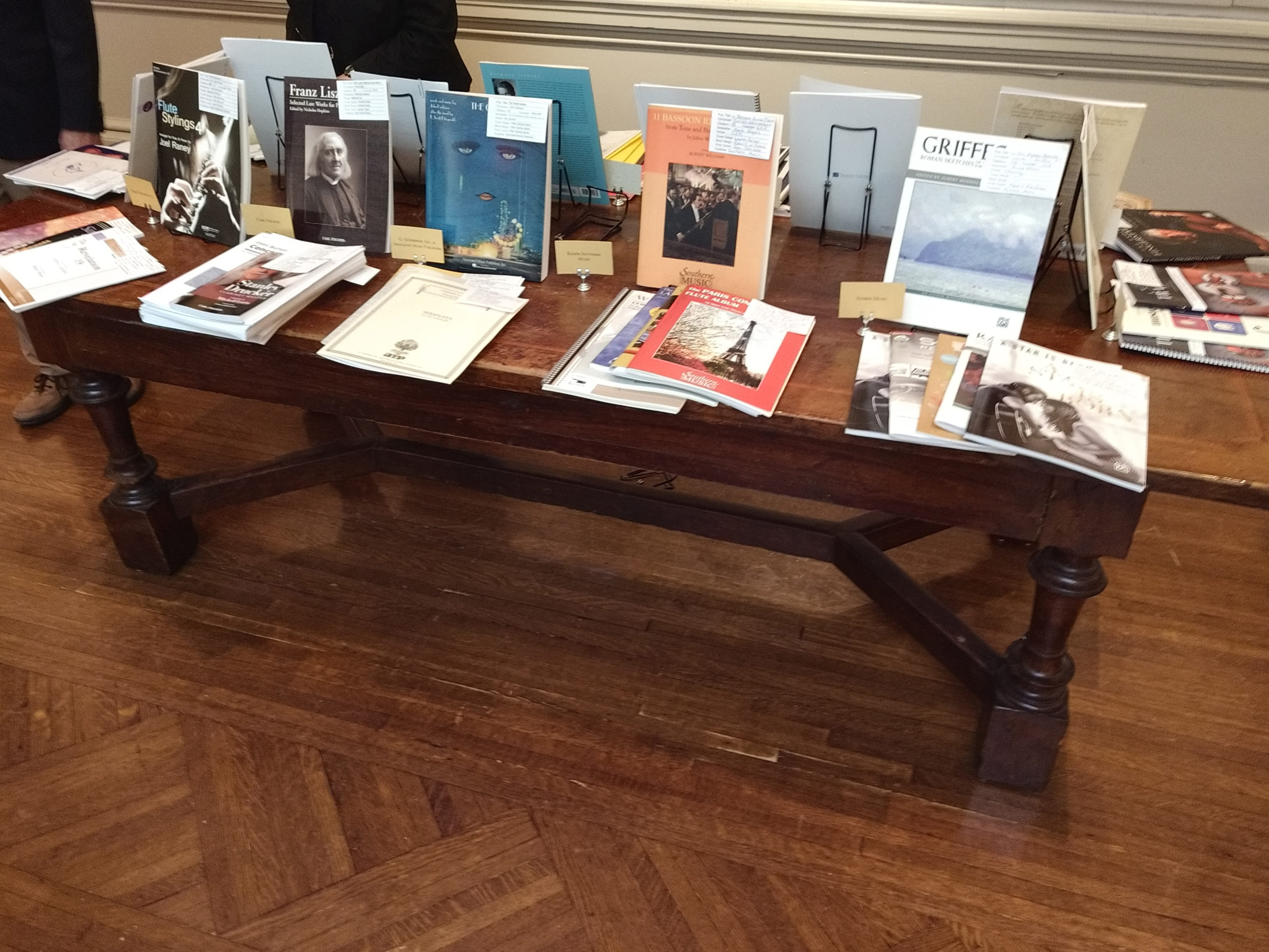 A brown wooden table that has stacks of publications on it